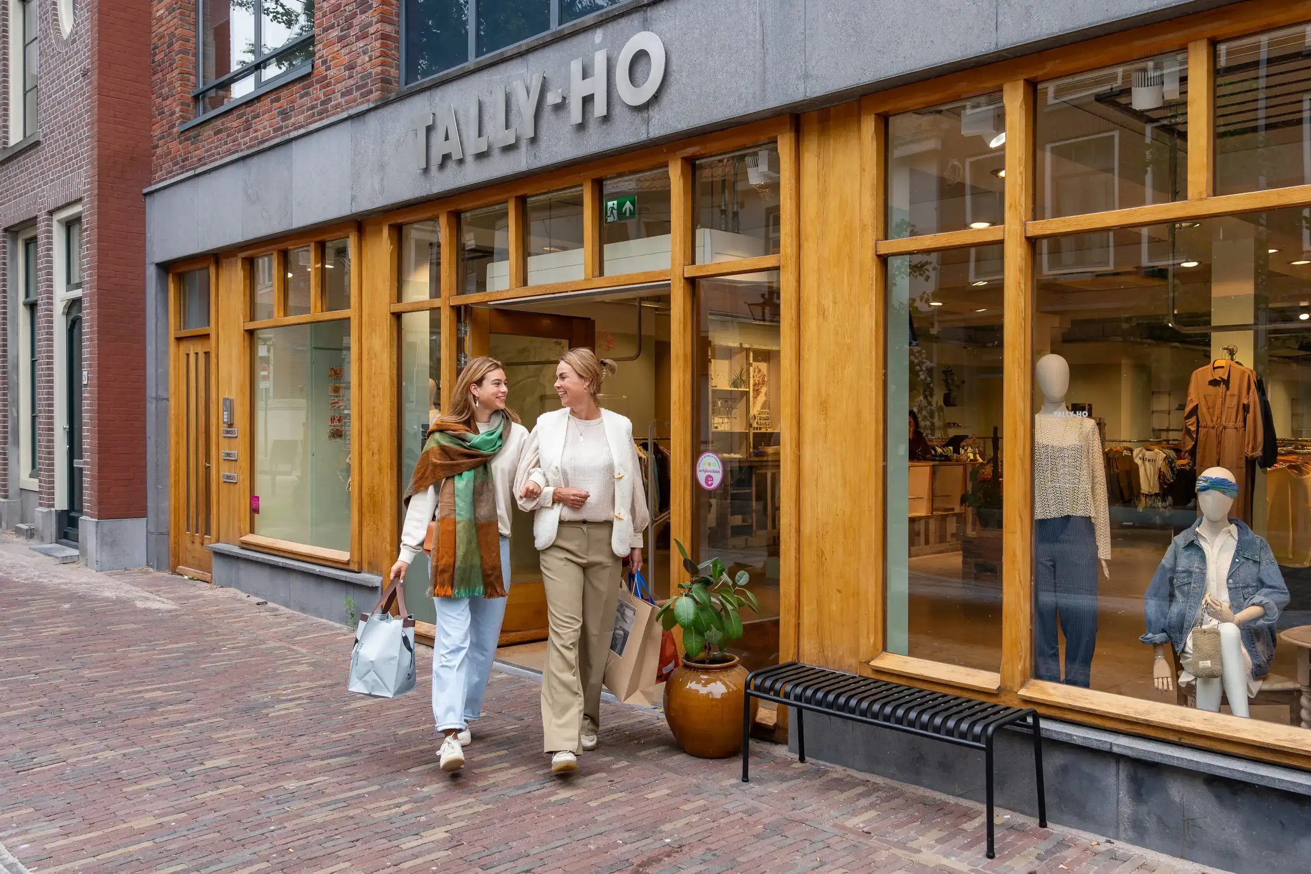 Vrouwen lopen met winkeltassen voor een winkel